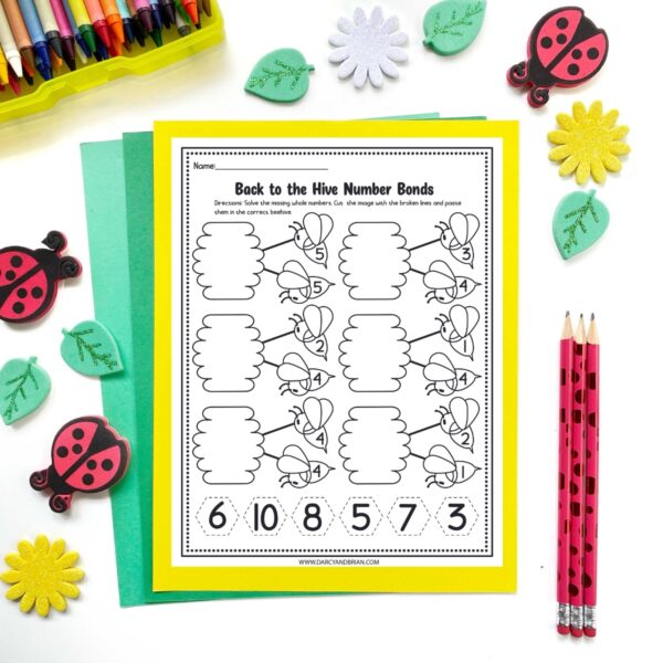Mockup of number bond worksheet featuring bees and hives on top of yellow and green papers. Spring manipulatives and pencils around the page.