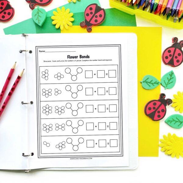 Flower themed math worksheet mockup in a white three ring binder with pencils and spring erasers around it.