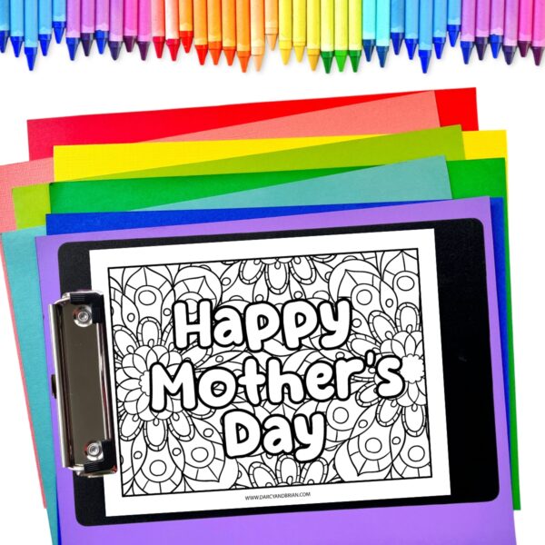 One Happy Mother's Day coloring page on a clipboard laying on colored sheets of paper. Crayons line the top of the image.